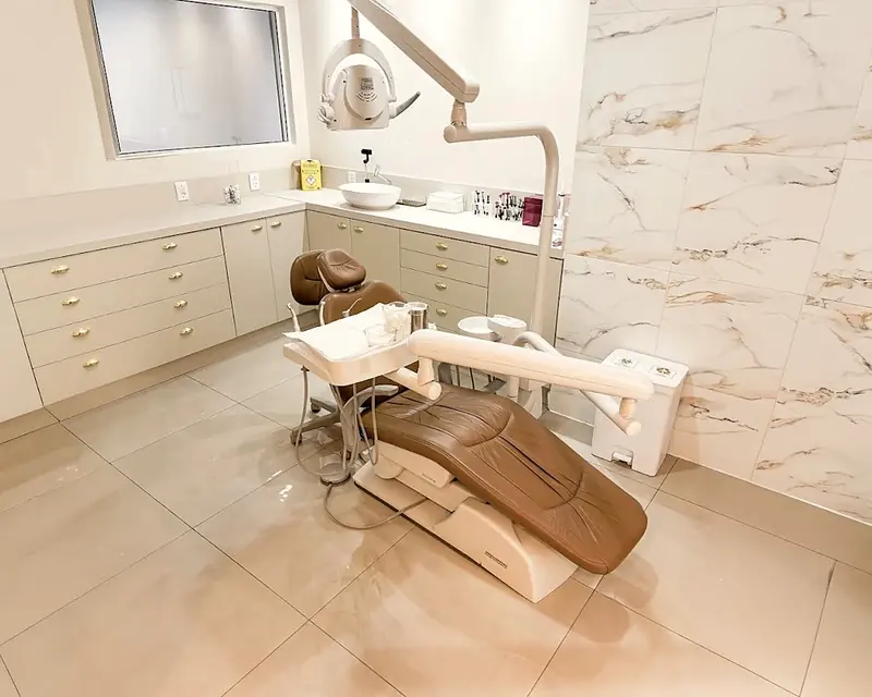 Sala de atendimento do consultório, com cadeira caramelo e parede de mármore