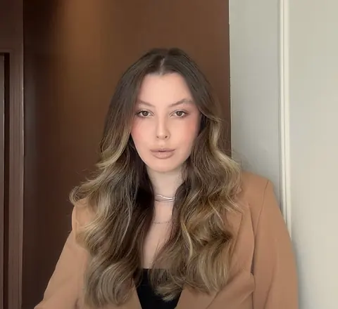 Dra. Bruna Viana Costa de blazer caramelo no consultório